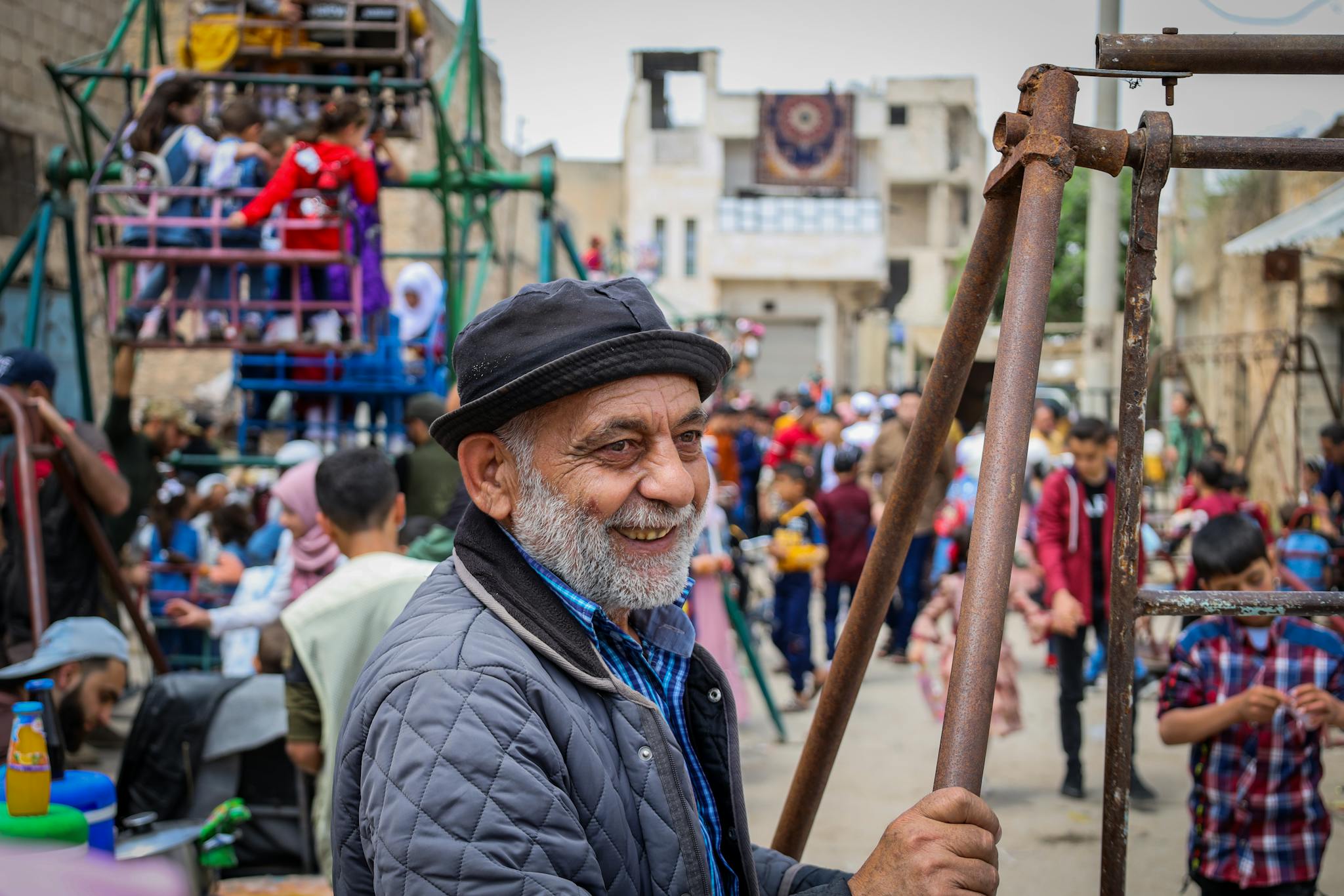 Happy elderly man enjoying a vibrant street festival in Idlib, Syria.