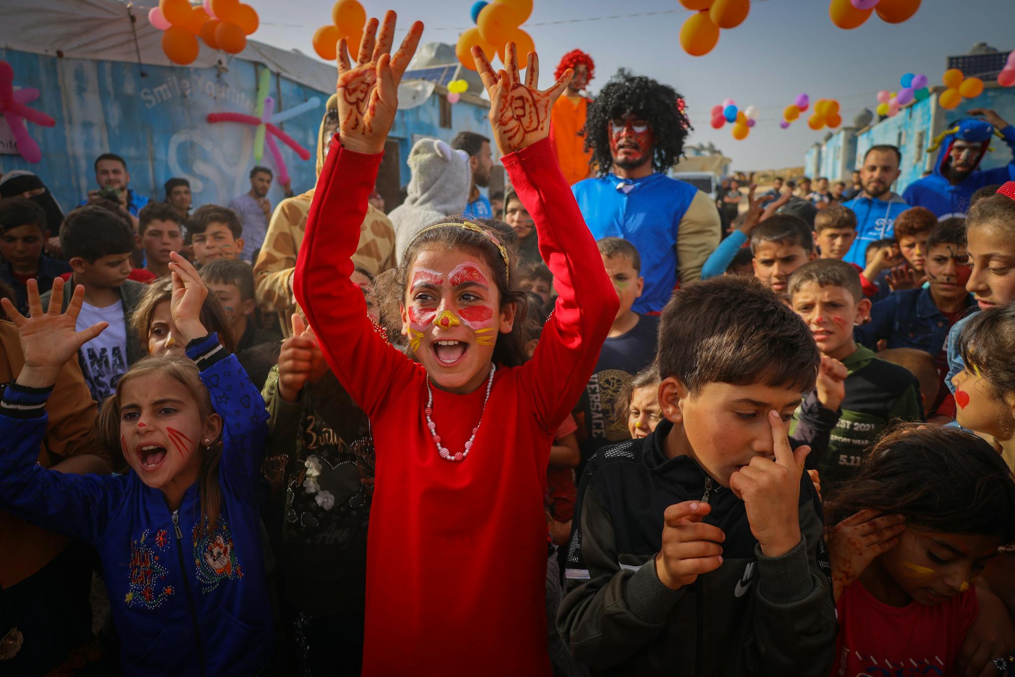 Vibrant children's festival with face painting and balloons in Idlib, Syria.